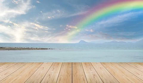 Empty wooden tabletop and view tropical beach with raibow over sea background Stock Photos