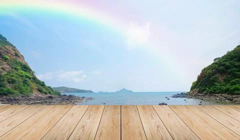 Empty wooden tabletop and view tropical beach with raibow over sea background Stock Photos