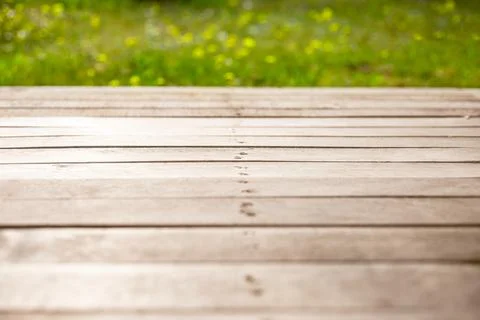 Empty wooden terrace rustic background with blurred field of green grass and Fotos de archivo