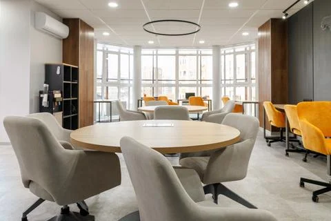 Empty working area in an open office. White round table surrounded by chairs in Stock Photos