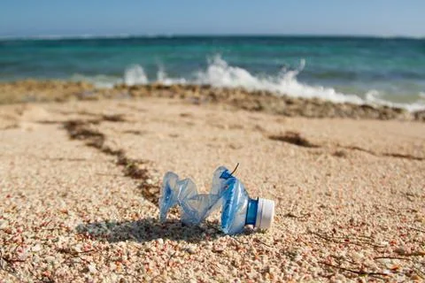 Empty, wrinkled plastic bottle in the middle of a beach Stock Photos