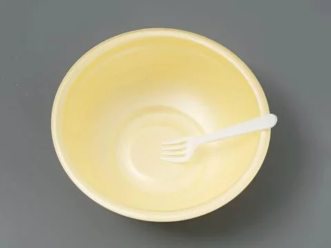Empty yellow bowl with a white fork on gray background Stock Photos