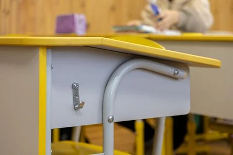 Empty yellow desk in an elementary school classroom with a student writing .. Stock Photos