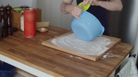 Emptying bread dough onto floured cutting board on wooden kitchen island worktop Stock Footage 344277170