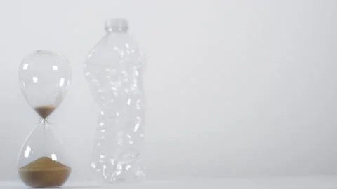 Emptying Sand Timer In Front Of Crushed Plastic Bottle Stock Footage 147686296