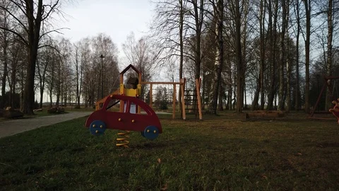 Empy children playground in the park, wind is blowing, toy car is swinging Stock Footage 122313202