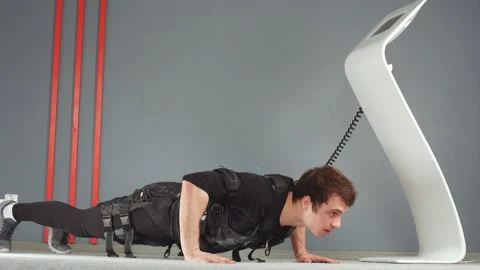 EMS male working out, doing push ups while connected to electric muscle Stock Footage 87108615