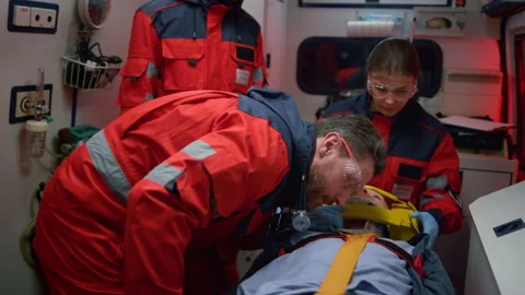EMS paramedics providing first aid procedure to patient in emergency vehicle Stock Footage 166907642