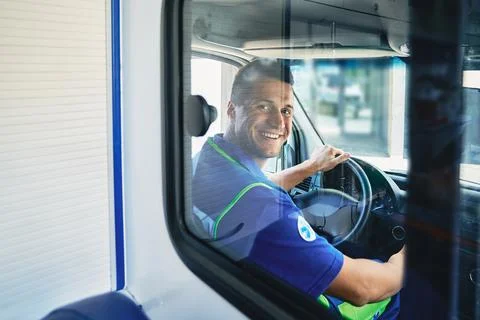 EMS. Smiling ambulance driver sitting in cab of ambulance vehicle, back view Stock Photos
