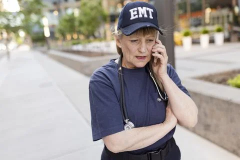 EMS worker talking on phone on sidewalk Stockfoto's
