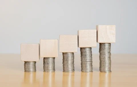 Emtpy wooden cube on top of stack of coins setting on wooden table. Calcula.. Stock Photos