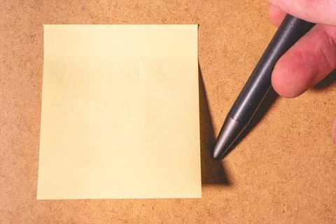 An emty sticky note on a brown background. Stock Photos