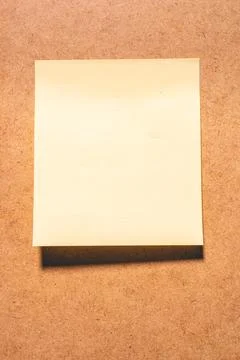 An emty sticky note on a brown background. Stock Photos