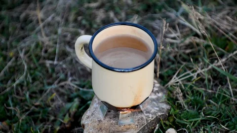The enameled mug is on the bottom of the stone heated with dry fuel Stock Footage 92483195