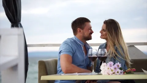 Enamored spouses caress each other in restaurant near the water, they drink wine Stock Footage