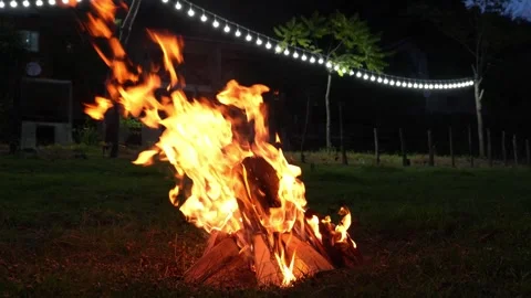 Enchanting bonfire flames dancing beneath twinkling string lights Stock Footage 286311418