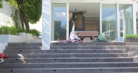 Encouraged by sun warming deck two women stretching straddle splits for Video stock 344325677