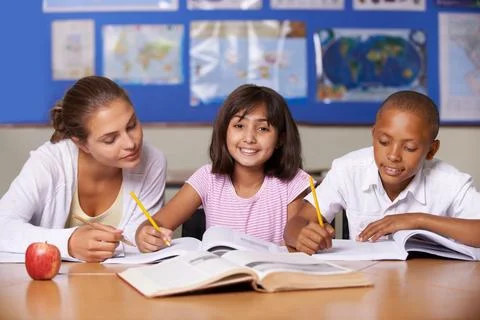 Encouraging their development. A young teacher sitting with her two ethnic Stock Photos