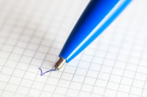 The end of a ballpoint pen on notebook background. Close-up Stock Photos