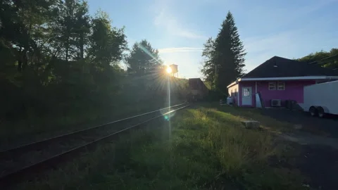 End of freight train rumbles past lonely New England station or outpost in fall Stock Footage 220571601