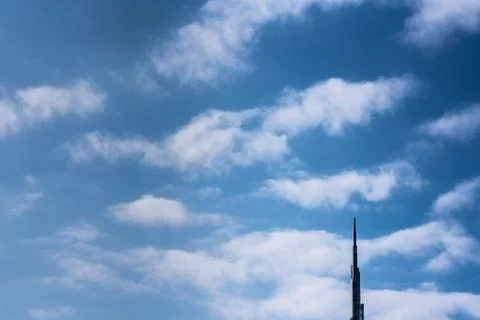 The end of a modern tower in a cloudy blue sky background Stock Photos