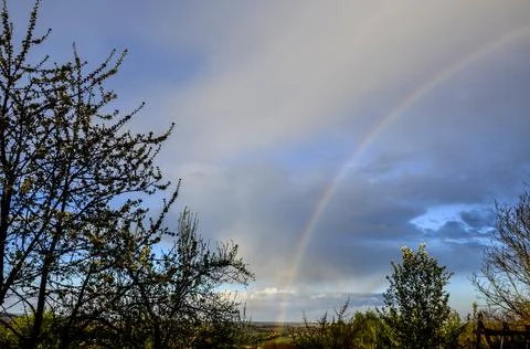 The end of a rainbow with a field in the foreground Stock Photos