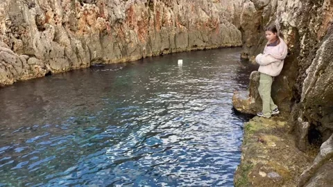 At the end of the stone path over a small bay stands a teenage girl. Stock Footage 263827998