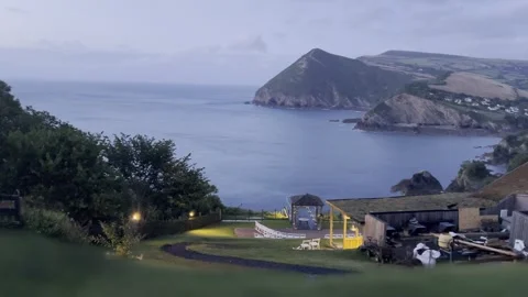 End of sunset over moody coastline in Devon at empty lit event venue Stock Footage 246475751