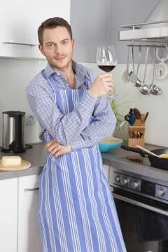 At the end of work: single man drinking glass of wine in the kitchen. Stock Photos