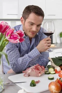 At the end of work: single man drinking glass of wine in the kitchen. Stock Photos