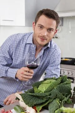 At the end of work: single man drinking glass of wine in the kitchen. Stock Photos