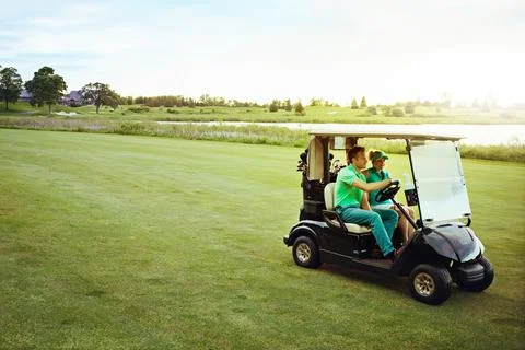 Ending off the week with a day on the course. a couple riding in a golf cart on Fotos de archivo