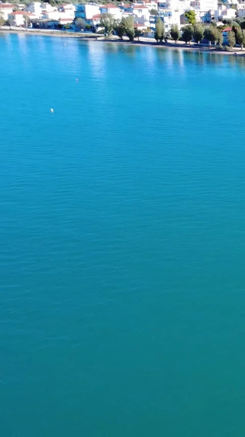 Endless Blue Sea Under Bright Sun with Distant Greek Island Village Stock Footage 343992547