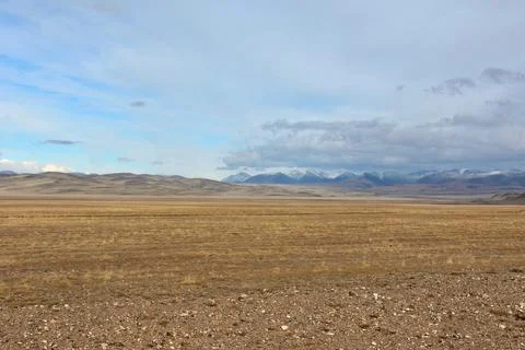 Endless flat steppe with a scattering of small stones at the foot of a ridg.. Stock Photos