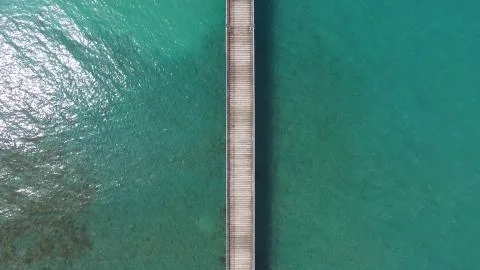 Endless pier extending to the ocean over turquoise lagoon Stock Photos