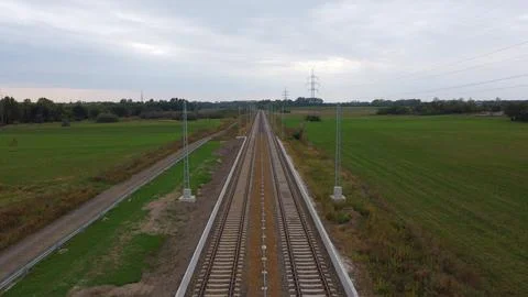 Endless Railway Through Green Fields and Overcast Sky Stock Photos