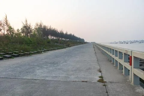 Endless seaside pathway lined with trees and ocean railing in Patenga, Bangl Stock Photos
