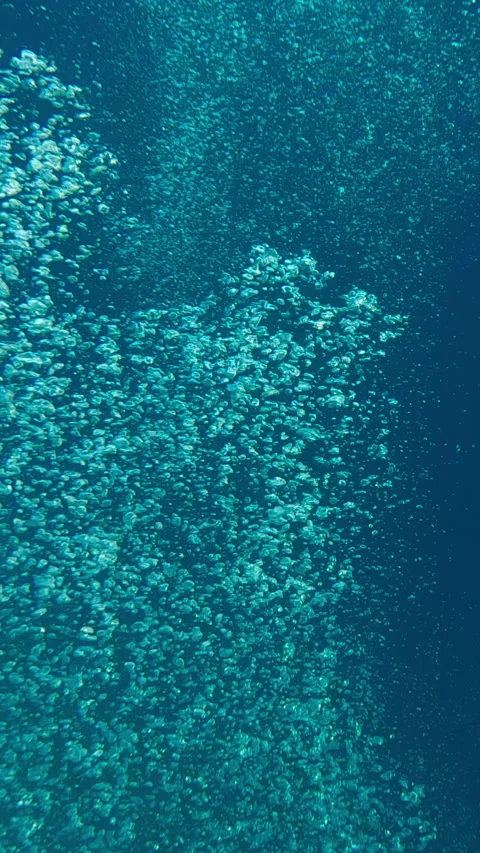 An endless stream of air bubbles rising upward from deep sea against blue water Stock Footage 332443020