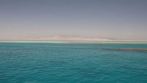 Endless turquoise water soft horizon golden shore fades into hazy mountains calm Stock Footage 310819259