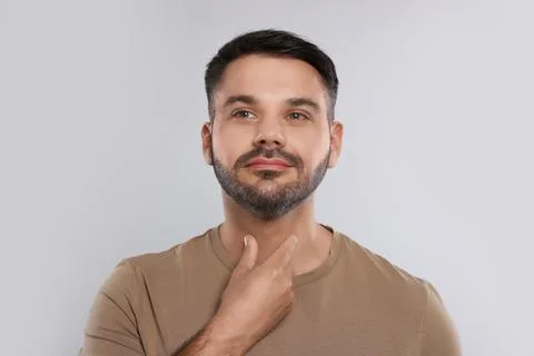 Endocrine system. Man doing thyroid self examination on light grey background Stock Photos