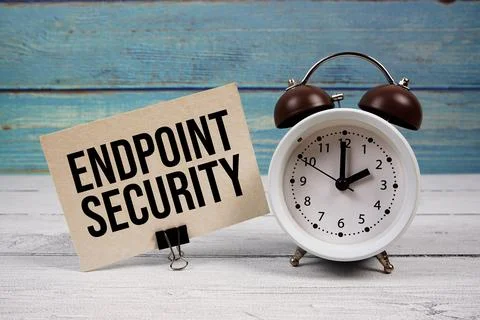 Endpoint Security text written on paper card with alarm clock on wooden bac.. Stock Photos