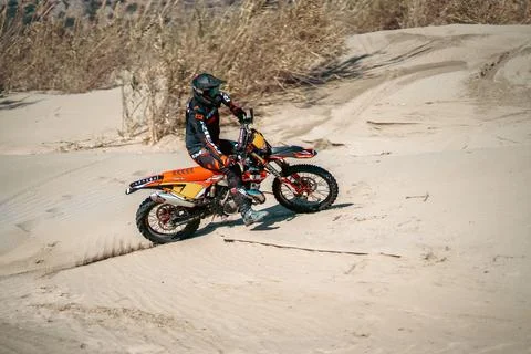 An enduro rider skillfully navigating his motorbike across the desert terrain. Stock Photos