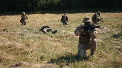 An enemy bullet wounds a warrior lying on the ground, and a special unit protect Stock Footage 204995633