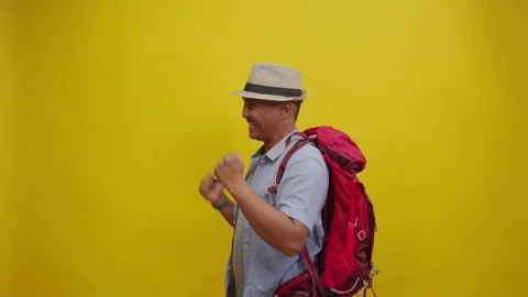 Energetic Backpacker Dancing Joyfully, Isolated on a Yellow Background Stock Footage 336996279
