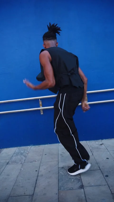 Energetic black man dancing hip hop against blue wall Stock Footage 345198122