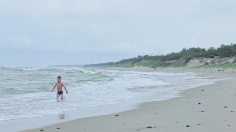An Energetic Child Having Fun on the Beach, Enjoying the Overcast Weather Video stock 315863803