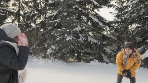 Energetic couple playing in the snow, throwing snowballs, enjoying the joyful Stock Footage 257825987