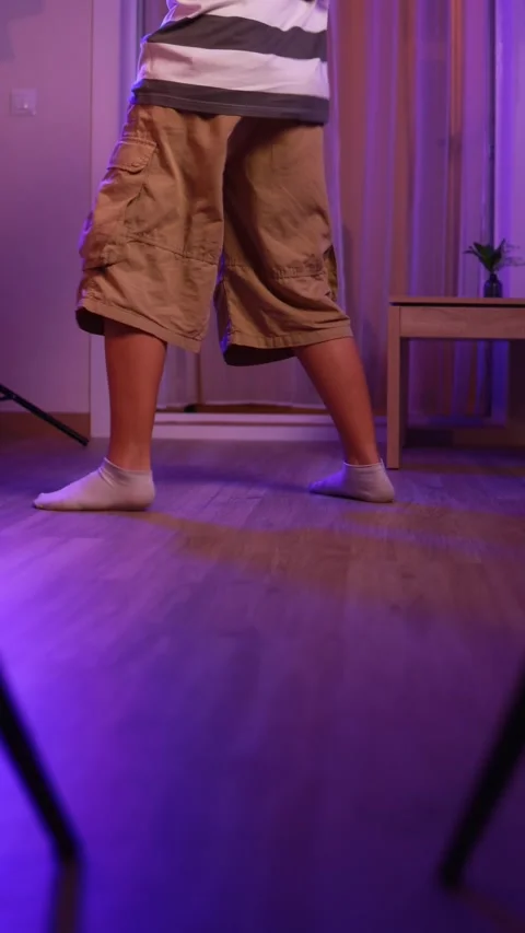 Energetic dancer showcasing breakdancing skills in a room illuminated with .. Stock Footage 305480173