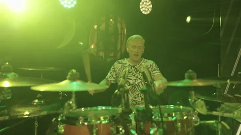Energetic drummer is playing drum kit on stage during gig of trendy youth rock Vídeo Stock 217801558