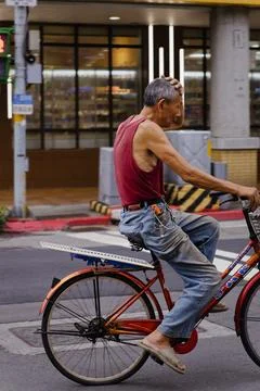 Energetic Elderly Man Riding Red Bicycle on Busy Taipei City Street Stock-Fotos
